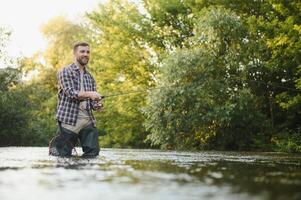 pêcheur captures une truite sur le rivière dans été photo