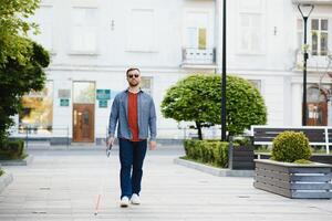 aveugle homme en marchant sur trottoir en portant bâton photo