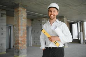 portrait de homme architecte à bâtiment placer. sur de soi construction directeur portant casque. réussi mature civil ingénieur à construction site avec copie espace. photo