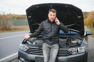 voiture cassé vers le bas sur le route, une homme appels le urgence service, une remorquer camion. photo