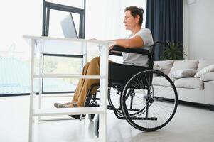 positif personnes âgées femme dans fauteuil roulant travail sur ordinateur portable, il pigiste, en ligne photo