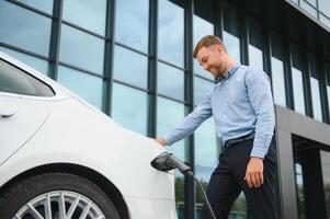 homme des charges un électrique voiture à le mise en charge station photo