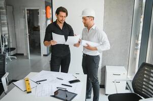 ingénieur ou architecte travail en équipe travail sur construction projet avec bâtiment modèle et plan dans bureau. construction concept. photo