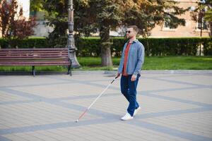 aveugle homme. gens avec invalidité, handicapé la personne et tous les jours vie. visuellement altéré homme avec en marchant bâton. photo
