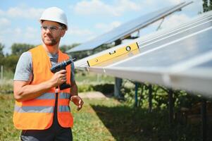 Masculin ouvrier avec solaire batteries. homme dans une protecteur casque. installation autonome solaire panneau système photo