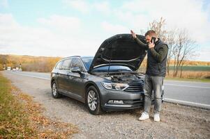 une homme ressentir stress car le sien voiture est cassé vers le bas photo