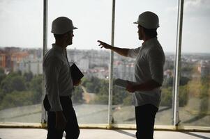 deux spécialistes inspecter commercial, industriel bâtiment construction placer. réel biens projet avec civil ingénieur photo