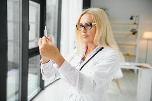 Sénior femme portant médecin uniforme en portant vaccin dose à clinique photo