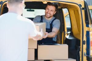 courrier un service pour le livraison de marchandises. Express un service une homme dans une uniforme livre des boites. le employé porte le commande Accueil à le client. photo