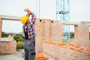 ouvrier du bâtiment en uniforme et équipement de sécurité a un travail sur le bâtiment photo