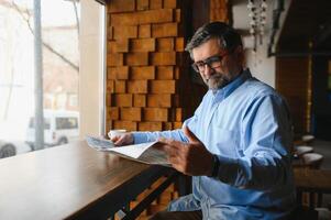 café Pause. homme en buvant café et en train de lire journal dans café bar photo