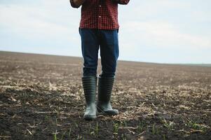 sale Les agriculteurs caoutchouc bottes en marchant sur le pluvieux route. photo