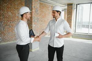 une de face vue de deux intelligent architectes avec blanc casques révision plans à une construction site sur une brillant ensoleillé journée photo