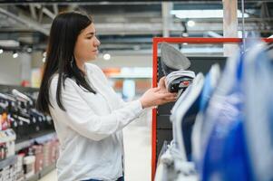 magnifique Jeune femme achat vapeur le fer dans magasin. photo