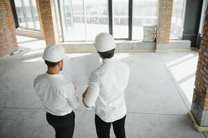deux spécialistes inspecter commercial, industriel bâtiment construction placer. réel biens projet avec civil ingénieur photo