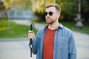 aveugle homme. gens avec invalidité, handicapé la personne et tous les jours vie. visuellement altéré homme avec en marchant bâton. photo