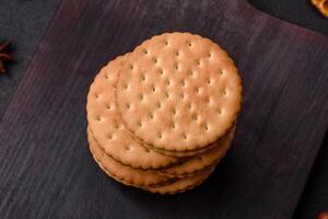 rond à pois casse-croûte casse-croûte biscuits avec crème sur une foncé béton Contexte photo