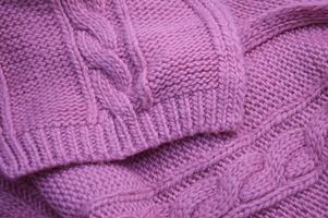 tricoté rose lilas chandail en tissu avec une magnifique texturé modèle. chaud la laine foulard. Contexte. photo