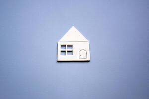 une petit maison fabriqué de blanc papier mensonges sur une lumière gris-bleu Contexte. photo