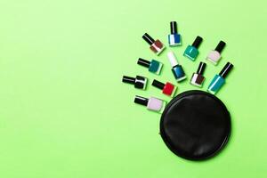 vue de dessus de l'ensemble de vernis à ongles et de vernis gel brillant tombés du sac de cosmétiques avec espace de copie sur fond vert. concept d'ongle à la mode photo