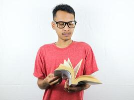 portrait de asiatique homme en portant livre avec en train de lire concentré expression. photo