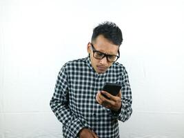 portrait de asiatique homme en portant mobile téléphone en lisant, dactylographie message avec concentrer visage expression. photo
