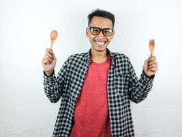 excité asiatique homme en portant cuillère et fourchette dans le sien mains photo