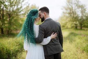 une barbu jeune marié et une fille avec vert cheveux sont en marchant photo