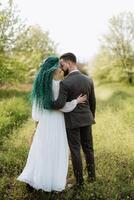 une barbu jeune marié et une fille avec vert cheveux sont en marchant photo