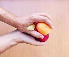 proche en haut de homme mains en portant rouge Pomme au dessus une bureau. photo