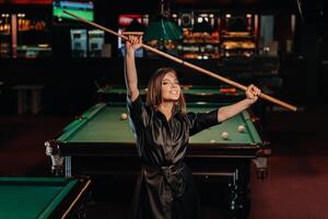 une fille avec une queue dans sa mains est permanent dans une billard club.russe billard photo