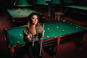 une fille dans une chapeau dans une billard club avec une queue dans sa mains.billard Jeu photo