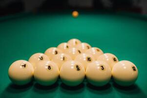 elles ou ils jouer bassin sur une vert table.le des balles sont mis dans une Triangle sur le tableau. photo