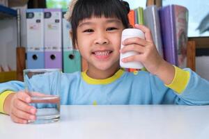 jolie petite fille mangeant de l'alpha oméga 3 ou une pilule de vitamine. suppléments vitaminiques pour les enfants pour une meilleure immunité. photo