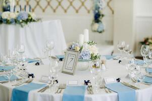 le de fête table est décoré dans lumière couleurs avec bleu serviettes et fleurs sans pour autant nourriture photo