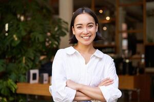 portrait de souriant asiatique fille dans blanc collier chemise, travail dans café, gérant restaurant, à la recherche sur de soi et élégant photo