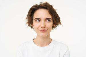 proche en haut portrait de brunette fille avec court la Coupe de cheveux, souriant et à la recherche content, posant plus de blanc Contexte photo