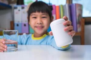 jolie petite fille mangeant de l'alpha oméga 3 ou une pilule de vitamine. suppléments vitaminiques pour les enfants pour une meilleure immunité. photo