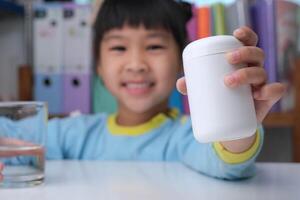 jolie petite fille mangeant de l'alpha oméga 3 ou une pilule de vitamine. suppléments vitaminiques pour les enfants pour une meilleure immunité. photo