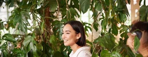 verticale coup de magnifique femme est assis dans café avec ordinateur portable, travaux ou études en ligne à cotravail espace, souriant détendu photo