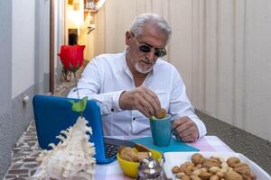 adulte homme est ayant petit déjeuner tandis que travail sur le ordinateur en plein air photo