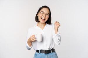 content dansant femme en buvant café ou thé de tasse. coréen fille avec tasse, permanent plus de blanc Contexte photo