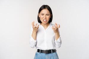 image de en colère énervé de femme tremblement de colère, serrer mains et grimaçant furieux, agacé et outré, permanent plus de blanc Contexte photo