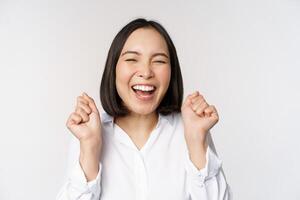 proche en haut visage portrait de dansant asiatique femme souriant, triomphant et célébrer avec content émotion, permanent plus de blanc Contexte photo