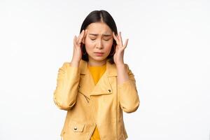 image de asiatique femme masser tête les temples avec concerné affronter, Souffrance mal de tête, migraine, permanent plus de blanc Contexte photo