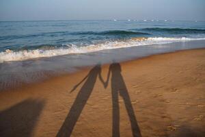 une couple sur le plage avec le coucher du soleil. marcher le long de le rivage. Extérieur des loisirs photo