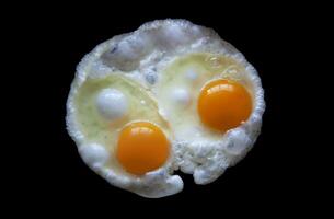 deux frit des œufs isolé sur une noir Contexte vue de au dessus photo