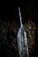 la glace stalactite la grotte froid. stalagmile dans le la grotte dans l'hiver. le glacé Royaume de le donjon. blanc lumière dans une foncé grotte. entrée à une grand fosse souterrain. photo