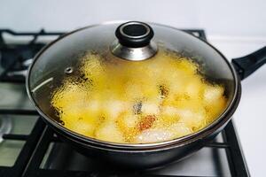 patates étant frit dans une poêle. fait maison Profond frit puces. photo