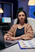 portrait de difficile travail directeur à la recherche dans caméra Faire au fil du temps. intelligent femme séance à sa lieu de travail dans le cours de en retard nuit heures Faire sa emploi. photo